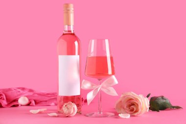 Renkli güllerle dolu bir şişe ve bir bardak pembe şarap.