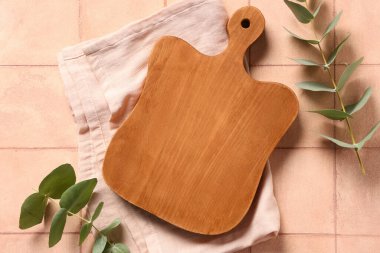 Peçete ve okaliptüs dallı boş kesim tahtası pembe döşemeli masa, üst görünüm