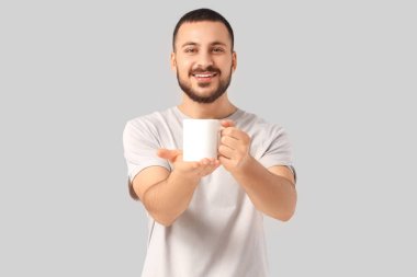 Gri arka planda bir fincan sıcak çayı olan yakışıklı genç adam.