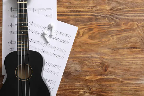 Ukulele, kulaklıklar ve ahşap arka planda notalar.