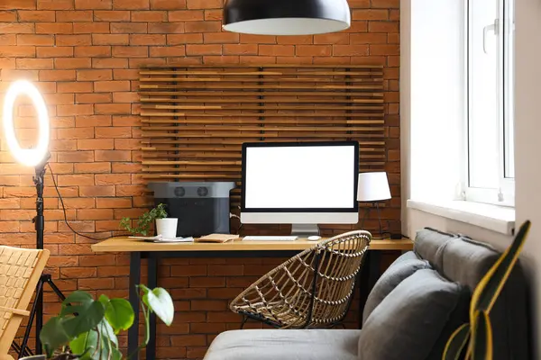 Giyim mağazasındaki tuğla duvarın yanında boş bilgisayar monitörü olan işyeri