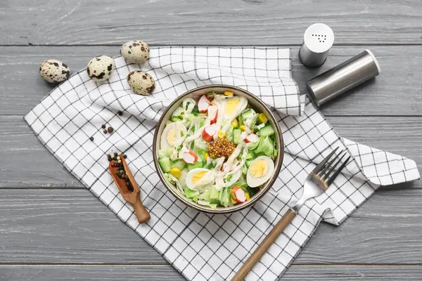 Bir kase salata ile yengeç sopası, mısır ve salatalık gri ahşap arka planda.