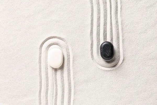 Üzerinde çizgiler olan beyaz kumlar üzerinde taşlar. Yin Yang konsepti