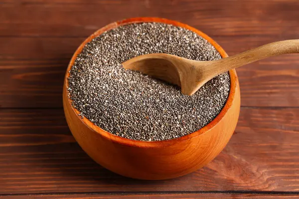 Ahşap zemin üzerinde chia tohumları ve kaşık ile kase