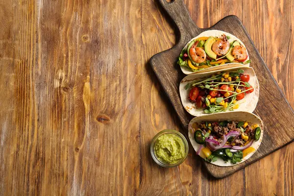 Ahşap zemin üzerinde farklı lezzetli tacolar bulunan tepsi.