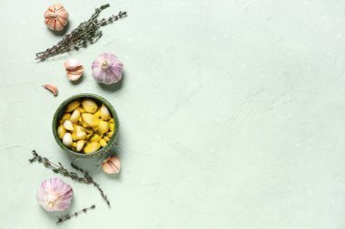 Yeşil arka planda kekik olan bir kase taze sarımsak yağı.