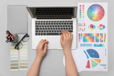 Dizüstü bilgisayar ve renk paletleri ile çalışan kadın grafik tasarımcısı, üst görünüm