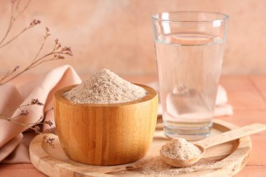 Masada Psyllium kabuğu tozu ve bir bardak su var.