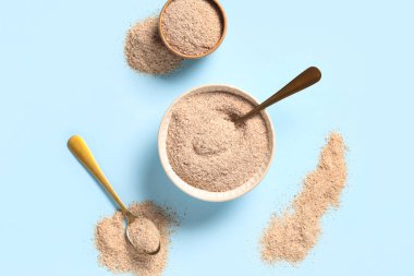 Mavi arka planda psyllium kabuk pudrası olan kaseler ve kaşıklar