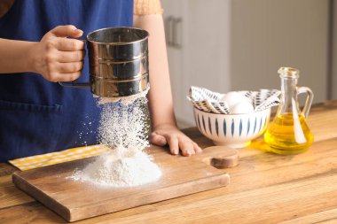 Mutfaktaki masada un elleyen bir kadın.