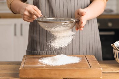 Mutfaktaki masada un elleyen bir kadın.