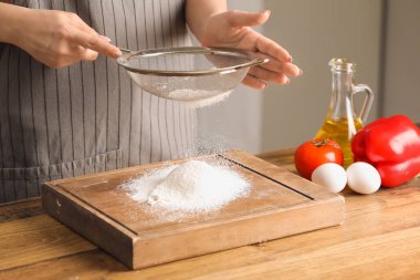 Mutfaktaki masada un elleyen bir kadın.