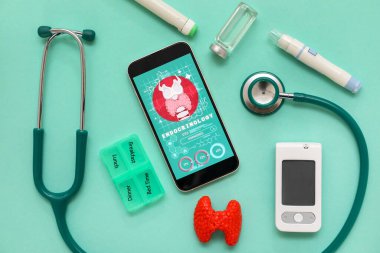 Tiroit bezi modelli cep telefonu, glukometre ve yeşil arka planda steteskop. Endokrinoloji kavramı