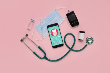 Glukometresi, steteskobu ve pembe arka planda tıbbi maskesi olan cep telefonu. Endokrinoloji kavramı