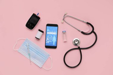 Glukometresi, steteskobu ve pembe arka planda tıbbi maskesi olan cep telefonu. Endokrinoloji kavramı