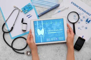 Elinde tablet bilgisayar ve tıbbi malzemeler olan bir kadın. Endokrinoloji kavramı