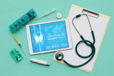 Yeşil arka planda tıbbi malzemeleri olan bir tablet bilgisayar. Endokrinoloji kavramı