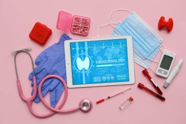 Pembe arka planda tıbbi malzemeleri olan bir tablet bilgisayar. Endokrinoloji kavramı