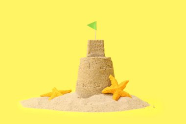 Güzel kumdan kale, sarı arka planda deniz yıldızları.