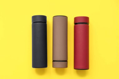 Sarı arka planda farklı modern termoslar