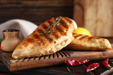 Lezzetli ızgara tavuk göğsü, kekik, kurutulmuş kırmızı biber ve ahşap zemin üzerinde biber.