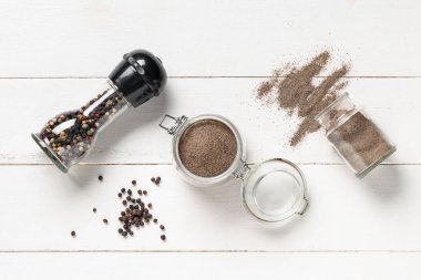 Karabiber tozlu kavanozlar ve beyaz ahşap arka planda karabiber.