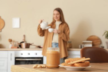 Fıstık ezmeli kavanoz, mutfakta genç bir bayana karşı, yakın plan.