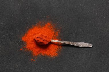 Siyah zemin üzerinde kırmızı biber tozu olan kaşık