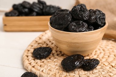 Beyaz ahşap arka planda kuru erikli kase ve kutu.