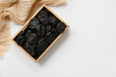 Beyaz zemin üzerinde kuru erik olan ahşap kutu.