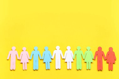 Sarı arka planda renkli kağıt insan figürleri. Çeşitlilik ve kapsama kavramı