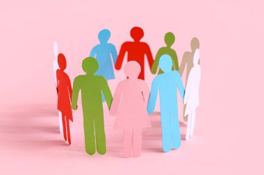 Kağıt insan figürleri pembe arka planda daireler çiziyor. Çeşitlilik ve kapsama kavramı