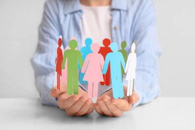 Işık masasında kağıt insan figürleri tutan bir kadın. Çeşitlilik ve kapsama kavramı