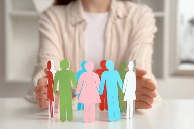 Işık masasında kağıt insan figürleri tutan bir kadın. Çeşitlilik ve kapsama kavramı