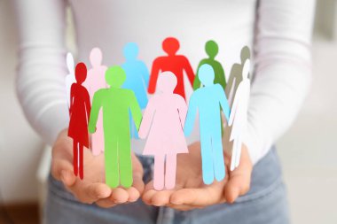 Kapalı alanda kağıt insan figürleri tutan bir kadın, yakın plan. Çeşitlilik ve kapsama kavramı