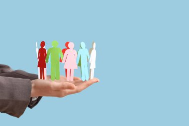 Renkli arka planda kağıt insan figürleri olan kadın eller. Çeşitlilik ve kapsama kavramı