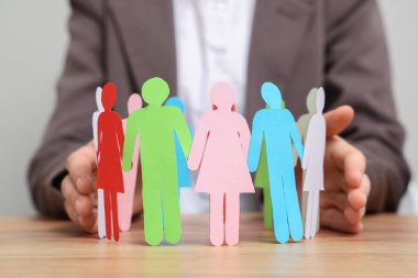 Ahşap masada kağıt insan figürlerini koruyan kadın, yakın plan. Çeşitlilik ve kapsama kavramı