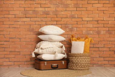 Odadaki tuğla duvarın yanında dekoratif yastıklı çanta ve sepet.