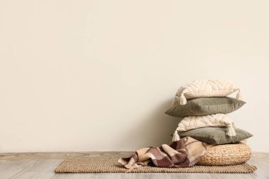 Dekoratif yastıklı puf ve oda duvarının yanındaki halıda ekose.