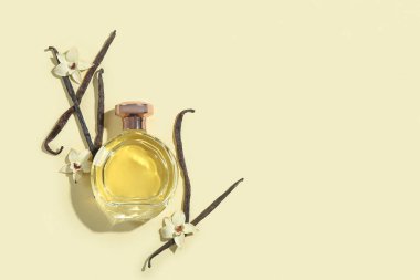 Renkli arka planda bir şişe parfüm, vanilya çubukları ve çiçekler.