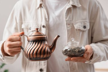 Çaydanlık ve kuru çayla evde genç bir adam, yakın plan.