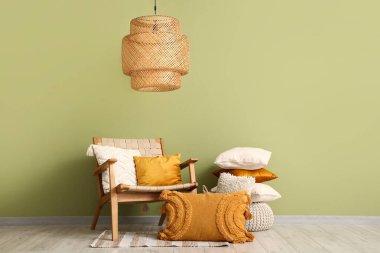 Oda yeşil duvarın yanında hasır koltuk ve yastıklar.