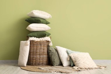 Yeşil duvarın yanındaki yastıklı sepet.