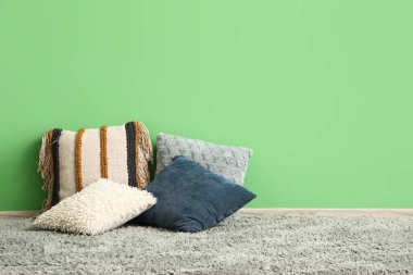 Halıdaki farklı yastıklar odada yeşil bir duvar taşıyor.