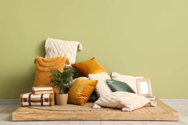 Yastıklar tezgahta, dekorlar yeşil duvarın yanında.