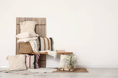 Yastıklı bank ve beyaz duvarın yanındaki oda.