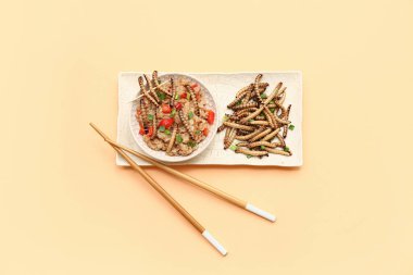 Bir kase kızarmış kurtlu pilav ve turuncu arka planda yeşil soğan.