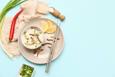 Bir kase kızarmış kurtlu pilav ve mavi arka planda yeşil soğan.