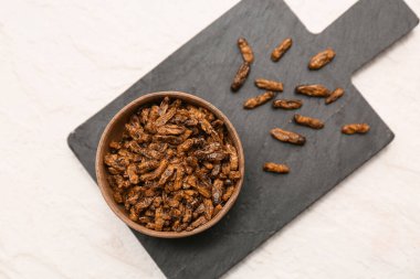 Beyaz arka planda kızarmış böcekler olan ahşap kase.