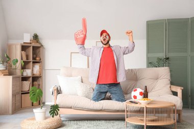 Duygusal futbol fanatiği evde televizyon izliyor.